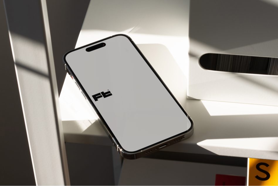 iPhone in hand with blank screen on white desk with shadows